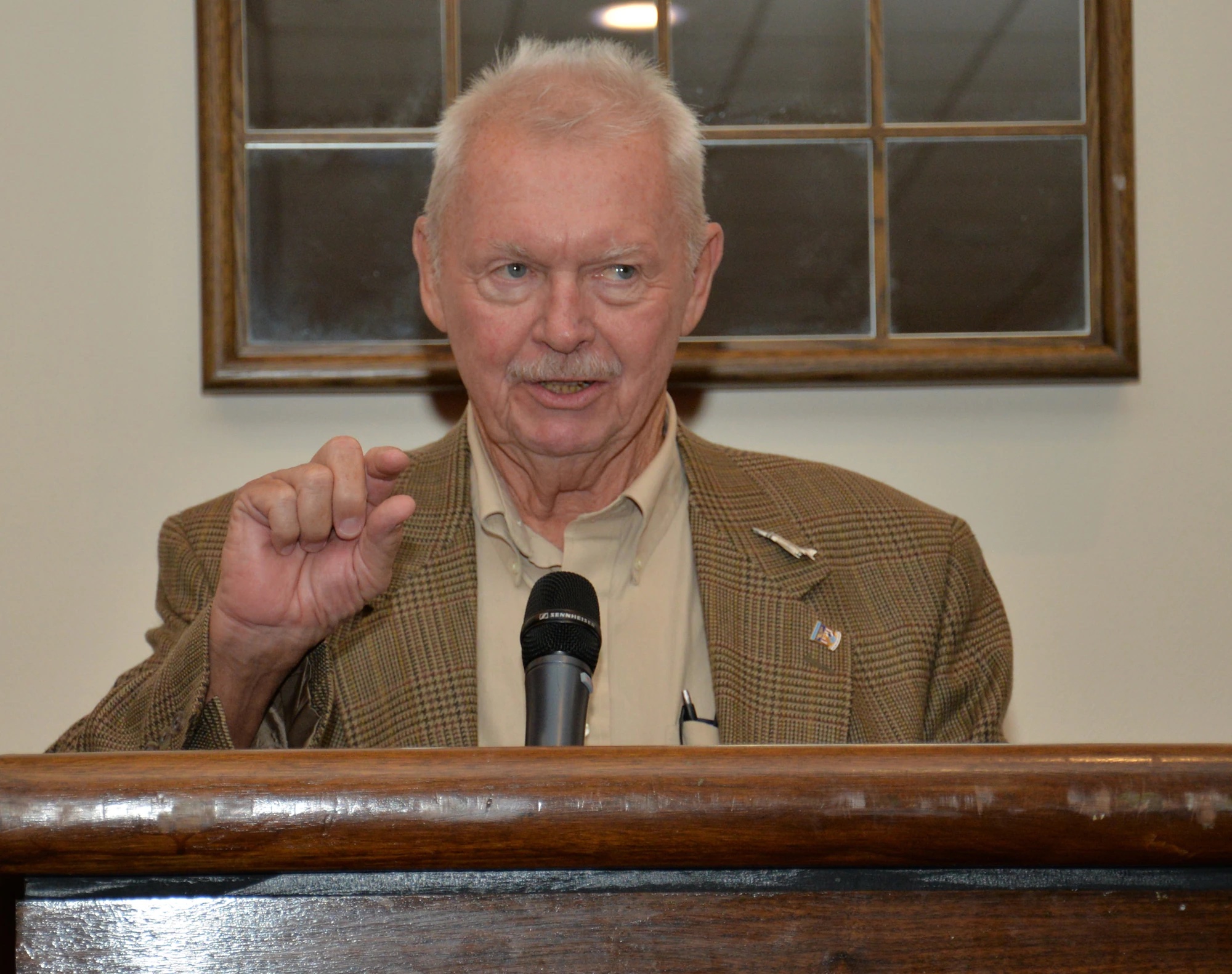 Older man giving a speech at a podium.