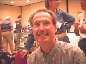 Man smiling in a collared shirt in front of a group of people.