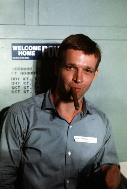 A man enjoying a cigar in front of "Welcome Home POV" sign.