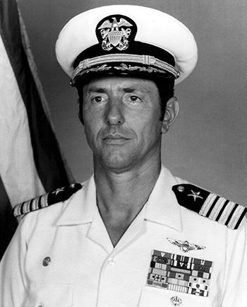 Man in a decorated U.S. Navy suit and cap.