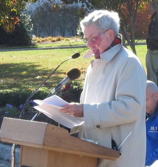 Older man speaking into a microphone at a podium.