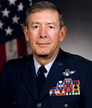 Man in a decorated U.S. Air Force suit in front of an American flag.