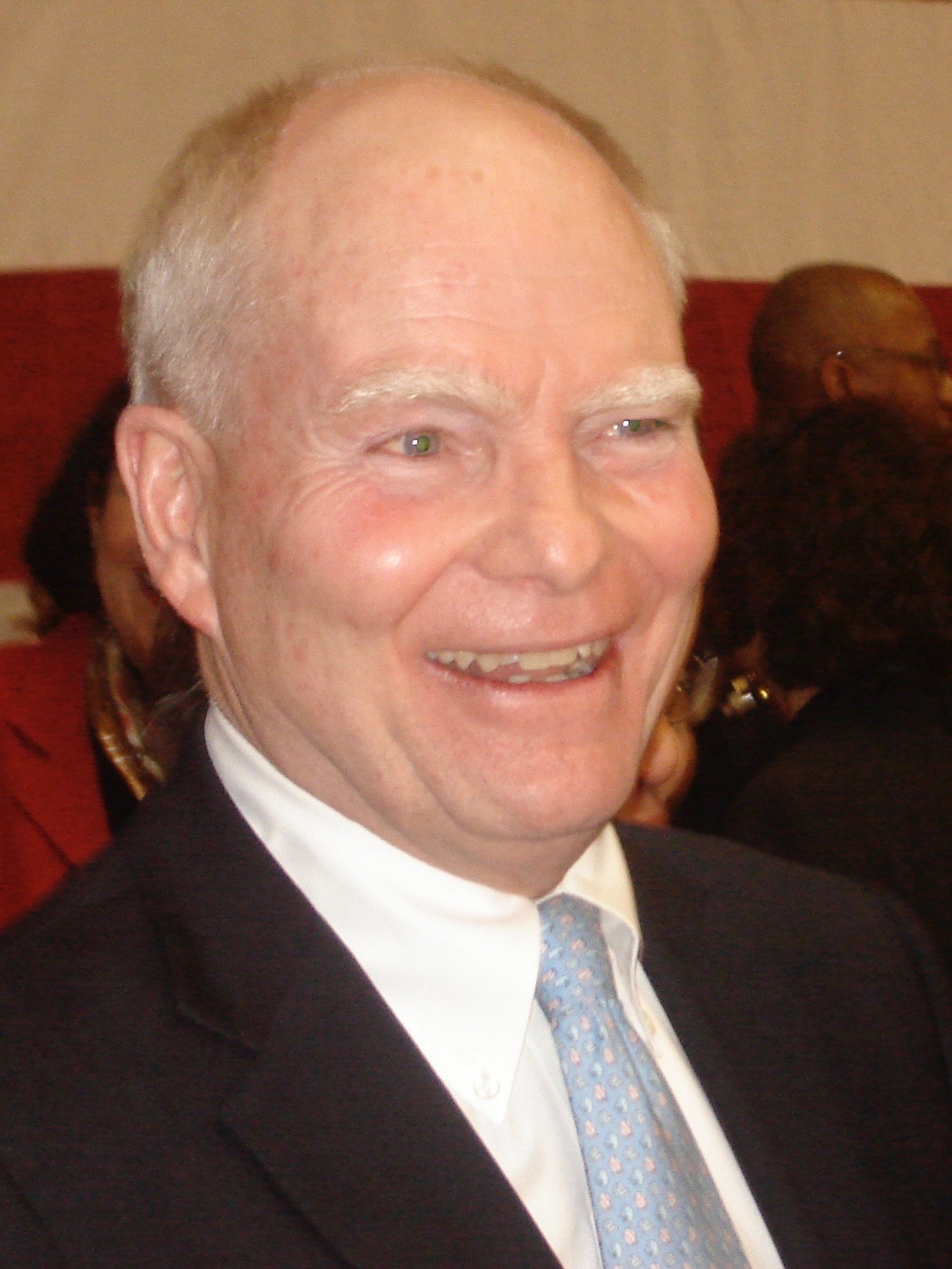 Older man smiling in a suit and tie.