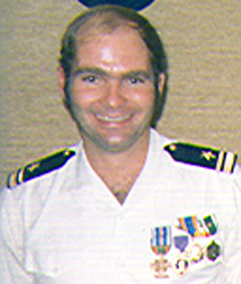 Man in a decorated white U.S. Navy uniform.