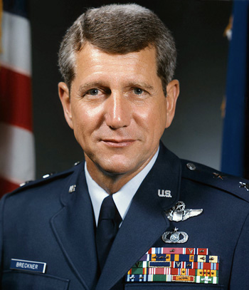 Man in a decorated U.S. Air Force suit in front of an American flag.