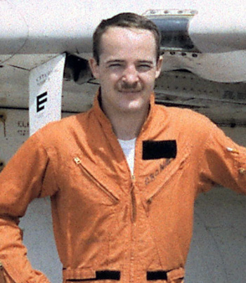 Man in an orange utility jumpsuit in front of an aircraft.