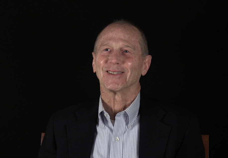 Man sitting in a collared shirt and suit.