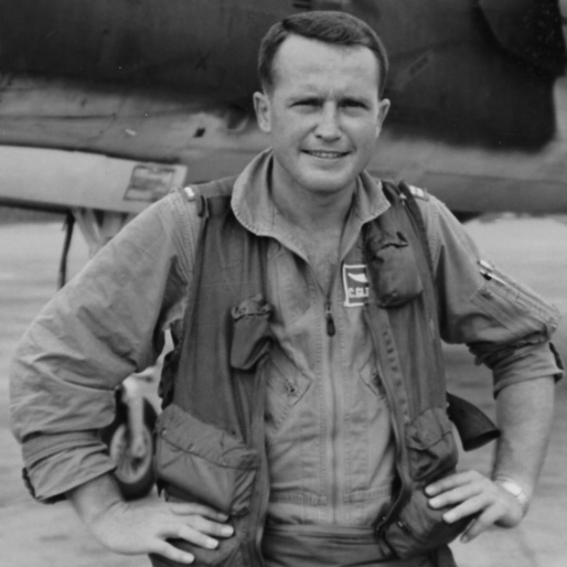 Man wearing piloting outfit standing in front of plane.