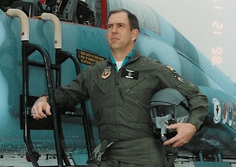 Man in pilot uniform standing next to a plane.