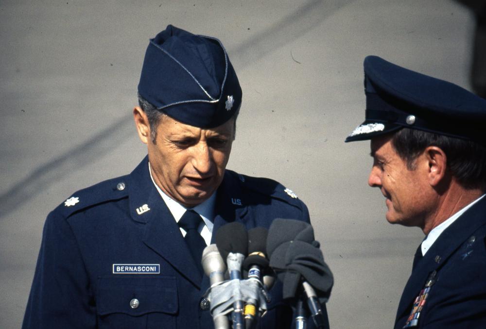 Two officers standing together. One officer speaks into a microphone.