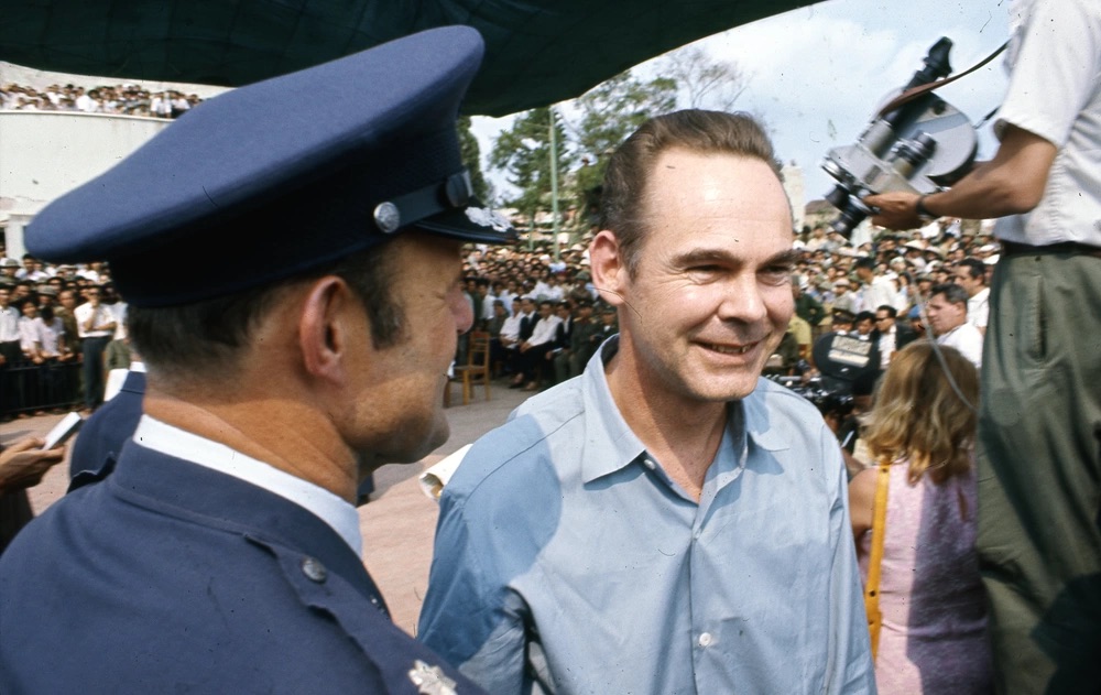 POW with an officer in front of a crowd.