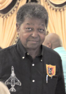 Older man in a collared shirt with an aircraft and badge printed on it.