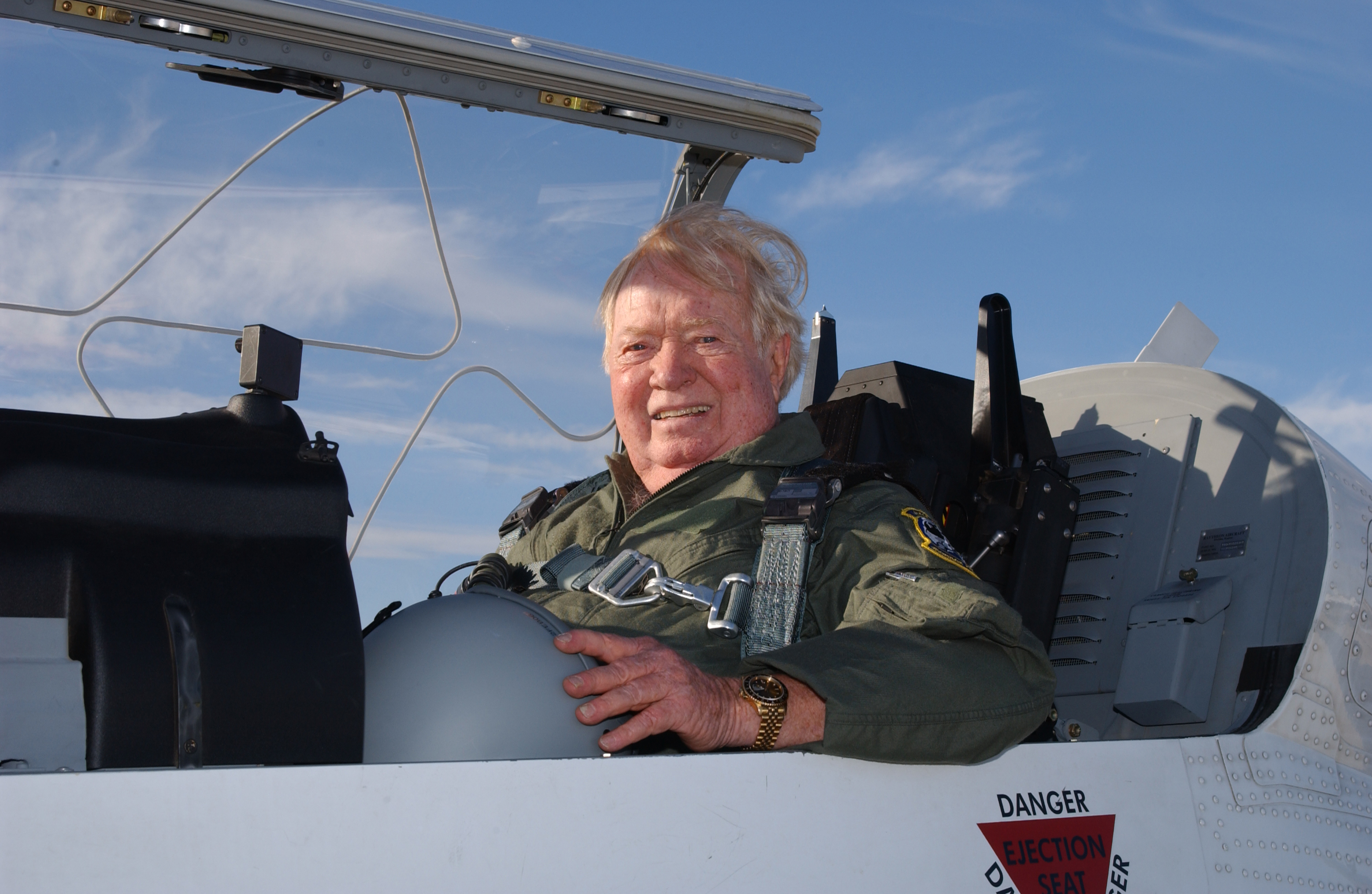 Older man in military utility suit in a military aircraft.