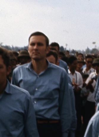 Man in blue collared shirt in a line in front of a crowd.