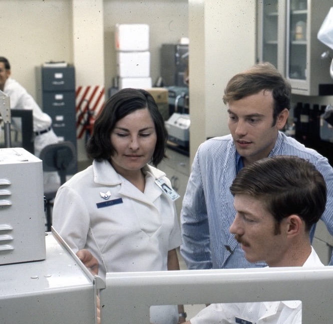 Two men and a woman looking at work in a laboratory.