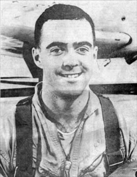 Man in front of an aircraft on a tarmac in a utility uniform.