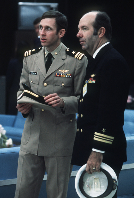 Two men in military suits holding caps. 