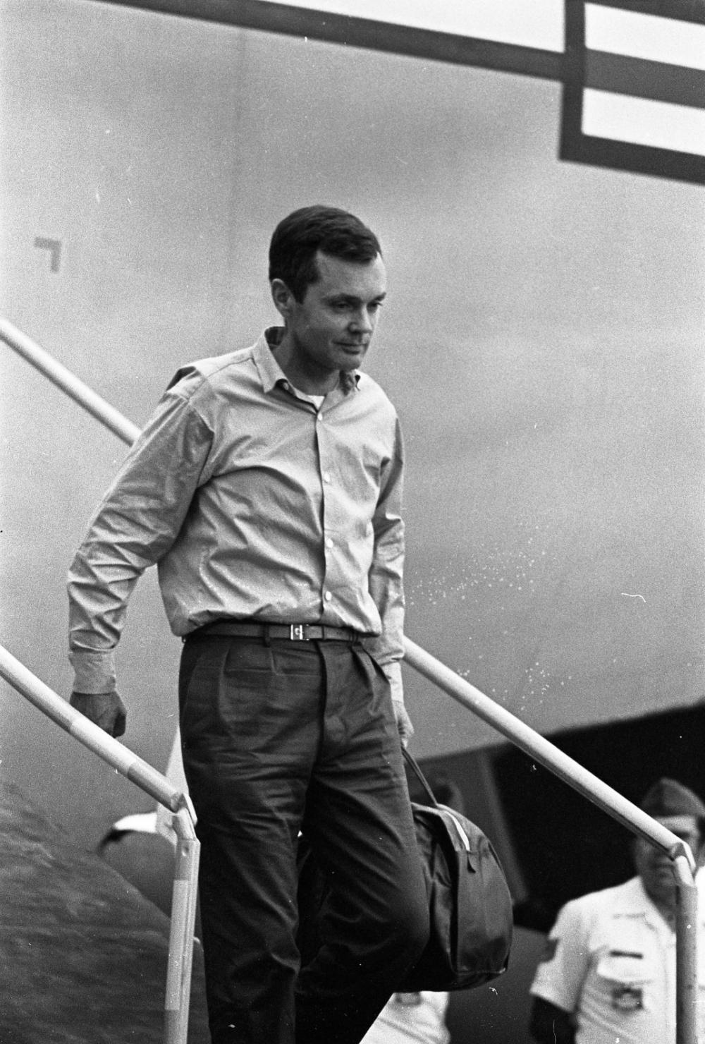 Man in a button down walking down ramp of aircraft.